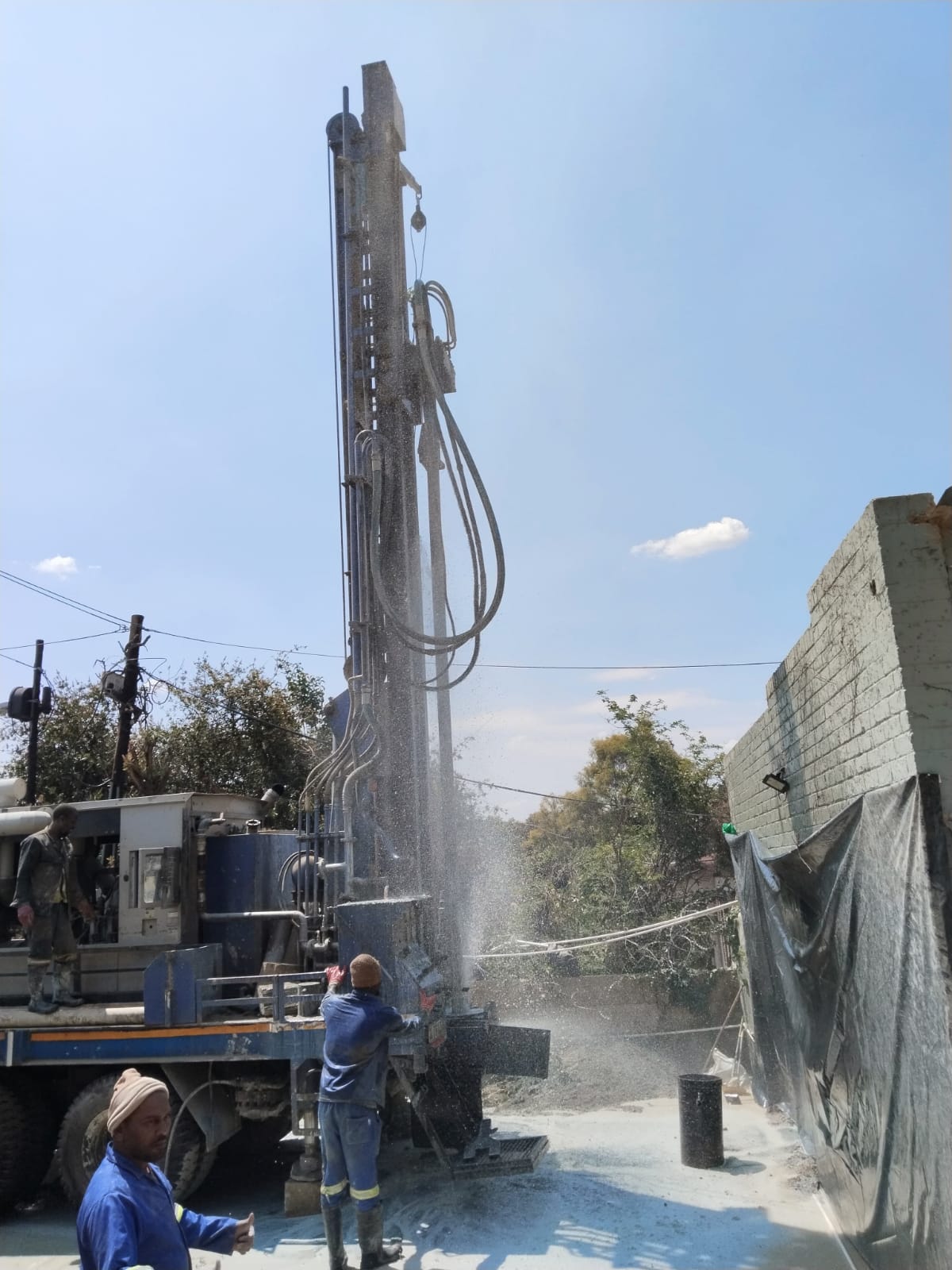 Borehole drilling rig spraying water mid-drill
